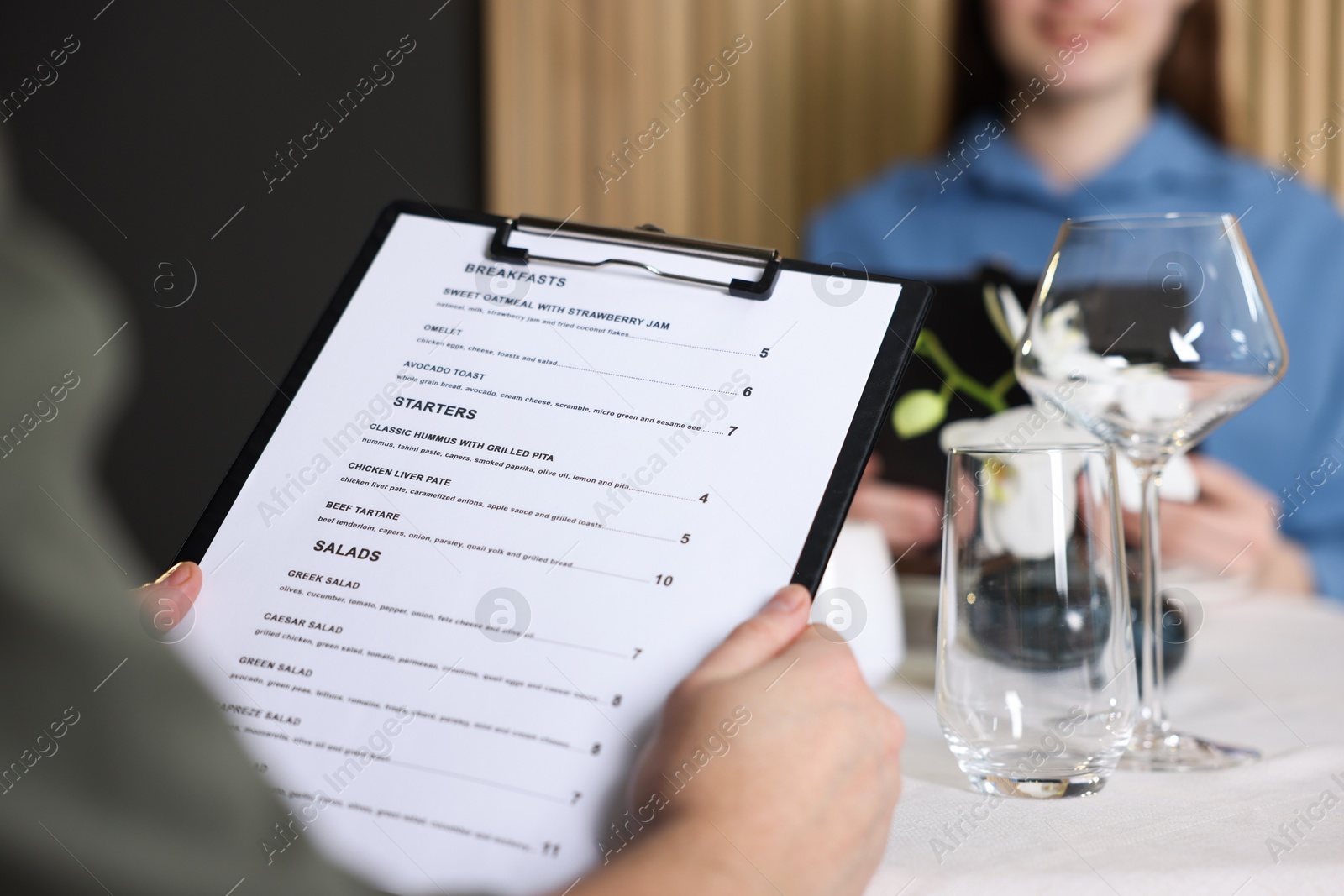 Photo of Couple choosing dishes from menu at table in restaurant, closeup