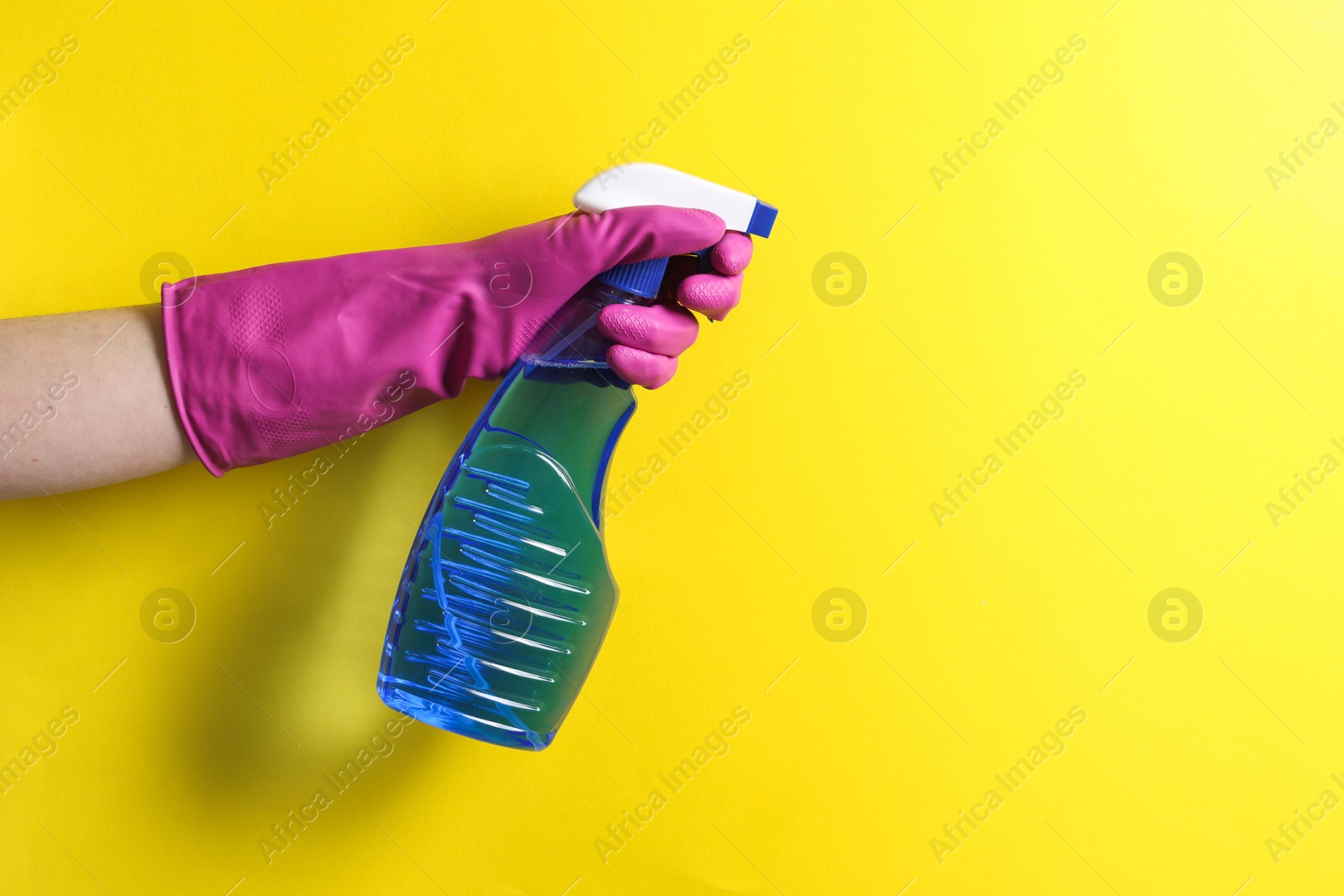 Photo of Woman with spray bottle of cleaning product on yellow background, closeup. Space for text