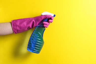 Photo of Woman with spray bottle of cleaning product on yellow background, closeup. Space for text