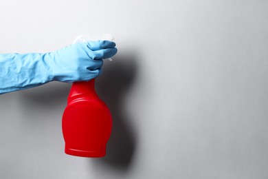 Photo of Woman with spray bottle of cleaning product on light grey background, closeup. Space for text