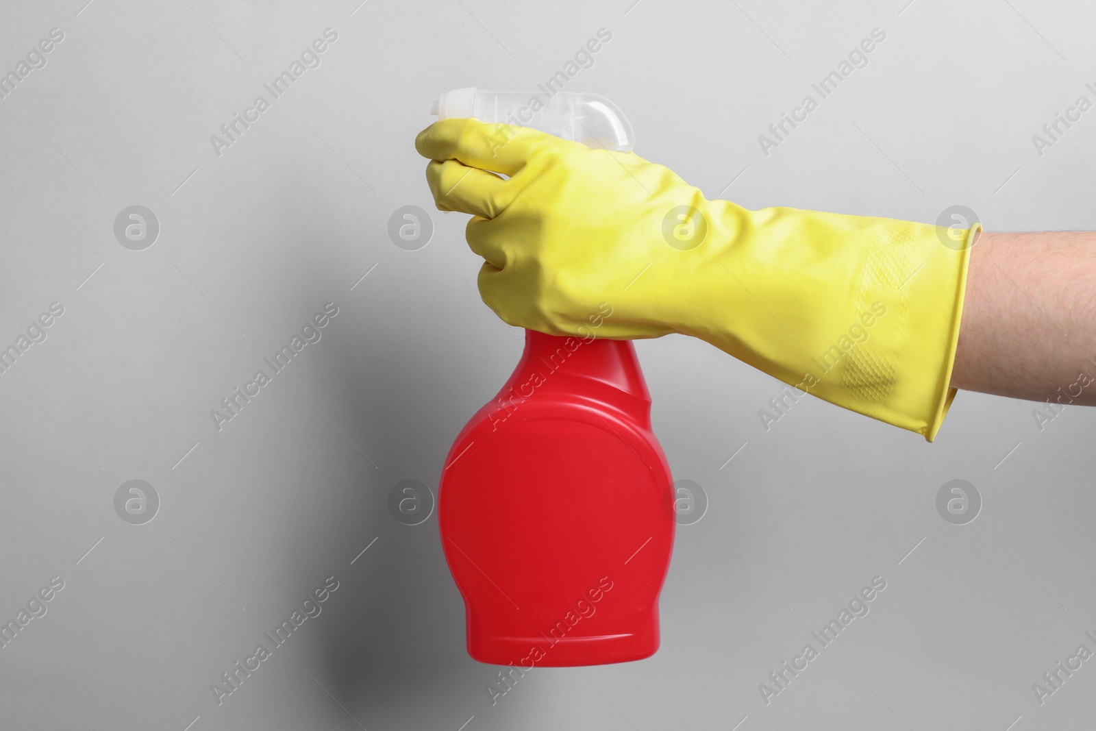 Photo of Woman with spray bottle of cleaning product on light grey background, closeup. Space for text