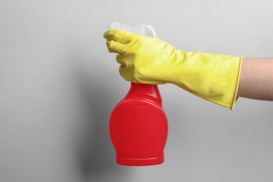 Photo of Woman with spray bottle of cleaning product on light grey background, closeup. Space for text