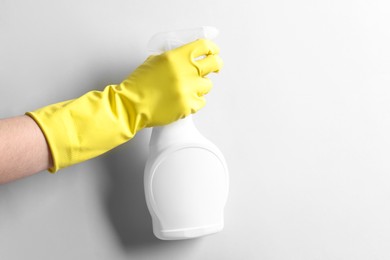 Photo of Woman with spray bottle of cleaning product on light grey background, closeup. Space for text