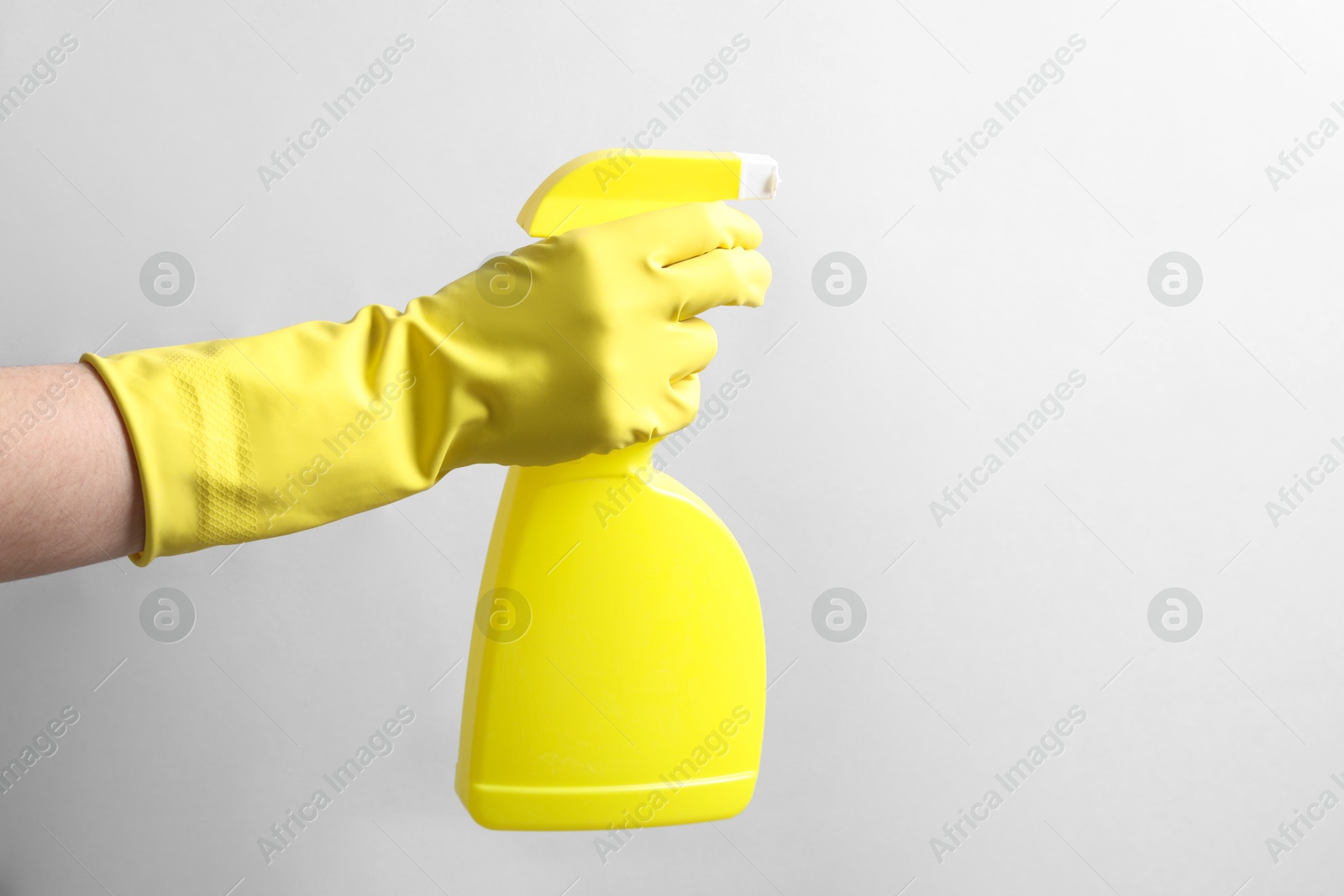 Photo of Woman with spray bottle of cleaning product on light grey background, closeup. Space for text