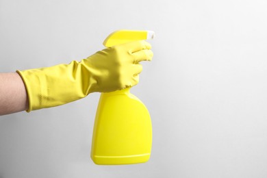 Photo of Woman with spray bottle of cleaning product on light grey background, closeup. Space for text