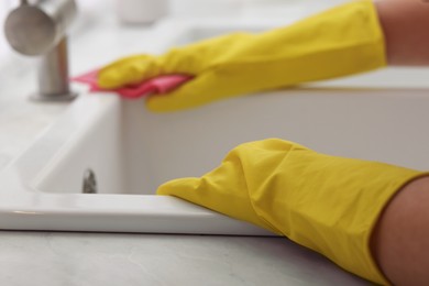 Photo of Woman cleaning sink with rag in kitchen, closeup