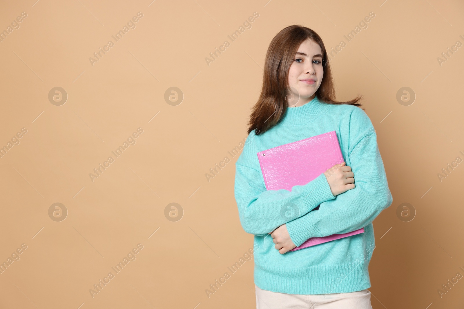 Photo of Portrait of teenage girl with folder on beige background. Space for text