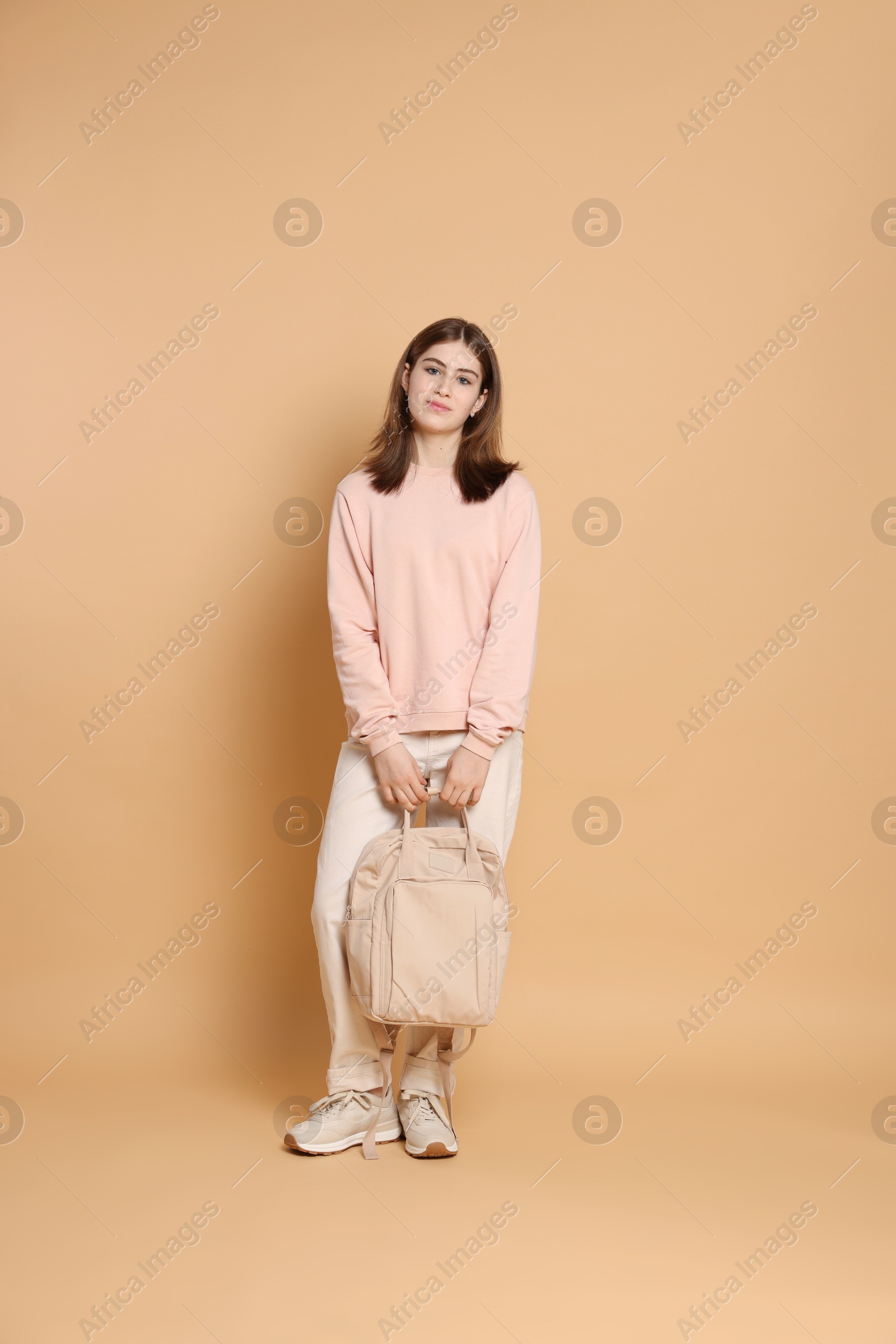 Photo of Portrait of teenage girl with backpack on beige background