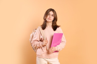 Photo of Portrait of teenage girl with backpack and folder on beige background