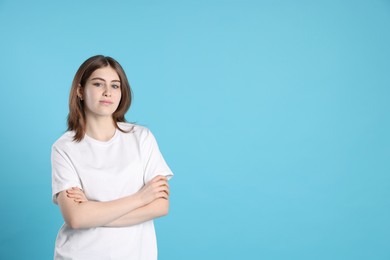 Photo of Portrait of beautiful teenage girl with crossed arms on light blue background. Space for text