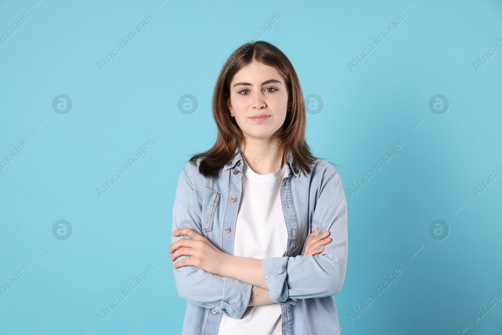 Photo of Portrait of beautiful teenage girl with crossed arms on light blue background