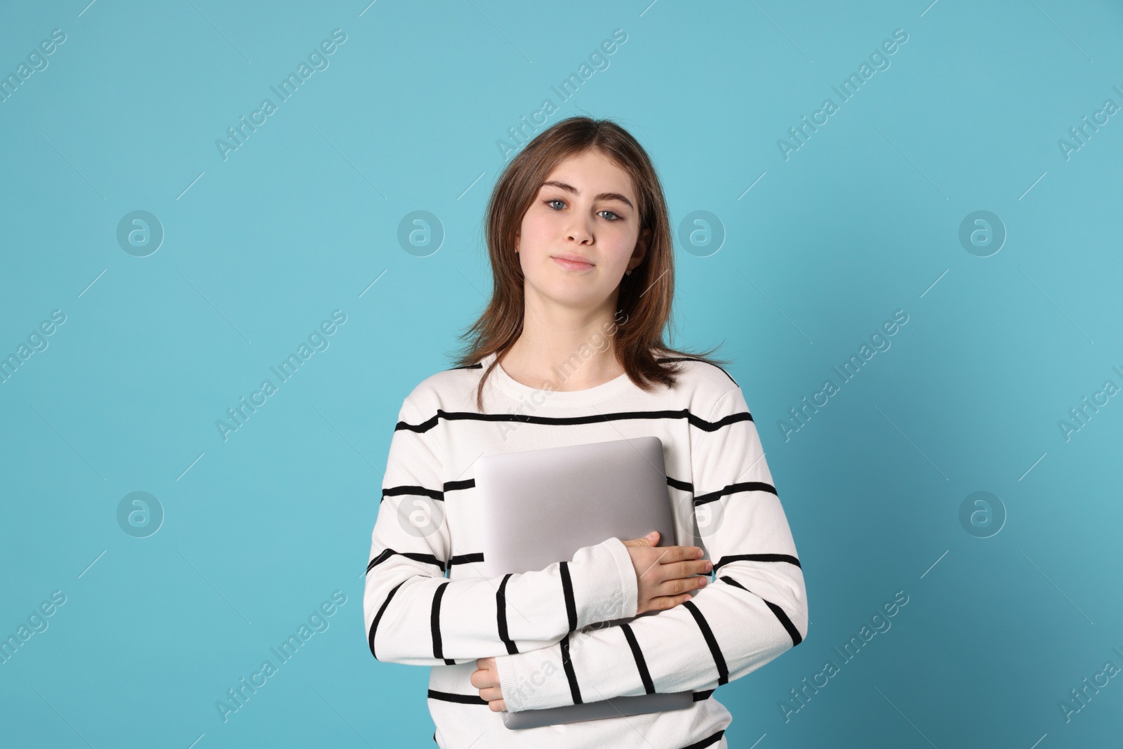 Photo of Portrait of teenage girl with laptop on light blue background