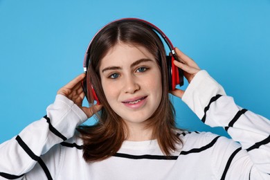 Photo of Portrait of teenage girl in headphones listening to music on light blue background