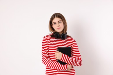 Photo of Portrait of teenage girl with headphones and notebook on light background