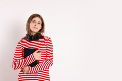 Photo of Portrait of teenage girl with headphones and notebook on light background. Space for text