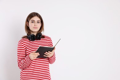 Photo of Portrait of teenage girl with headphones reading book on light background. Space for text