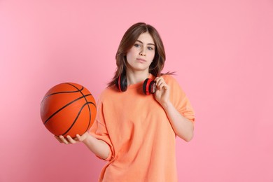 Photo of Portrait of teenage girl with headphones and basketball ball on pink background