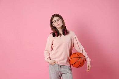 Photo of Portrait of teenage girl with headphones and basketball ball on pink background