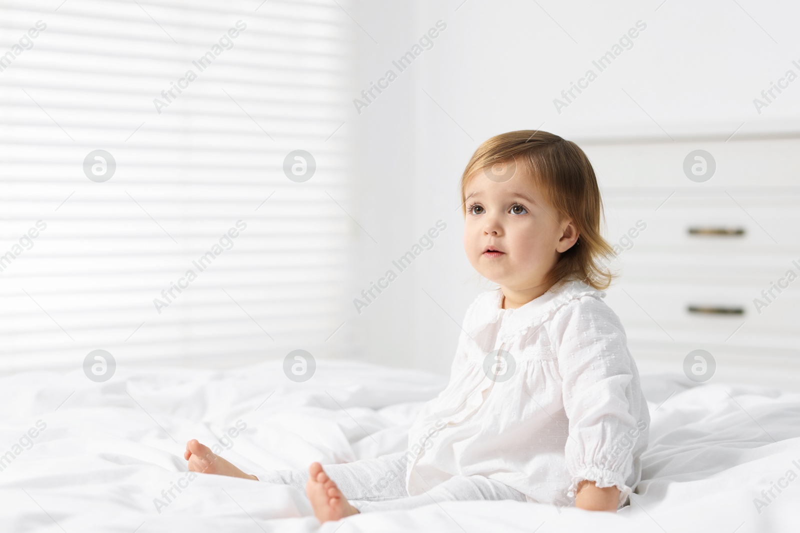 Photo of Cute little baby girl on bed at home. Space for text