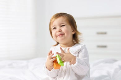 Photo of Cute little baby girl playing with toy on bed at home