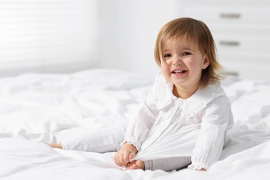 Photo of Cute little baby girl on bed at home. Space for text