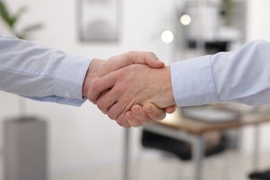 Photo of Businessmen shaking hands in agreement indoors, closeup