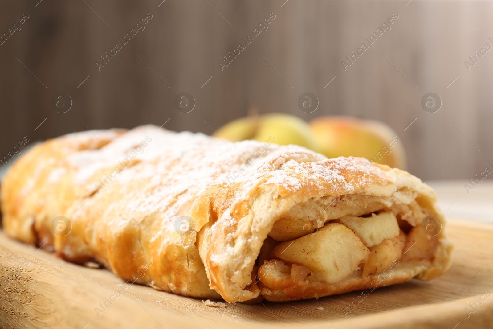 Photo of Delicious strudel with apples and powdered sugar on table, closeup