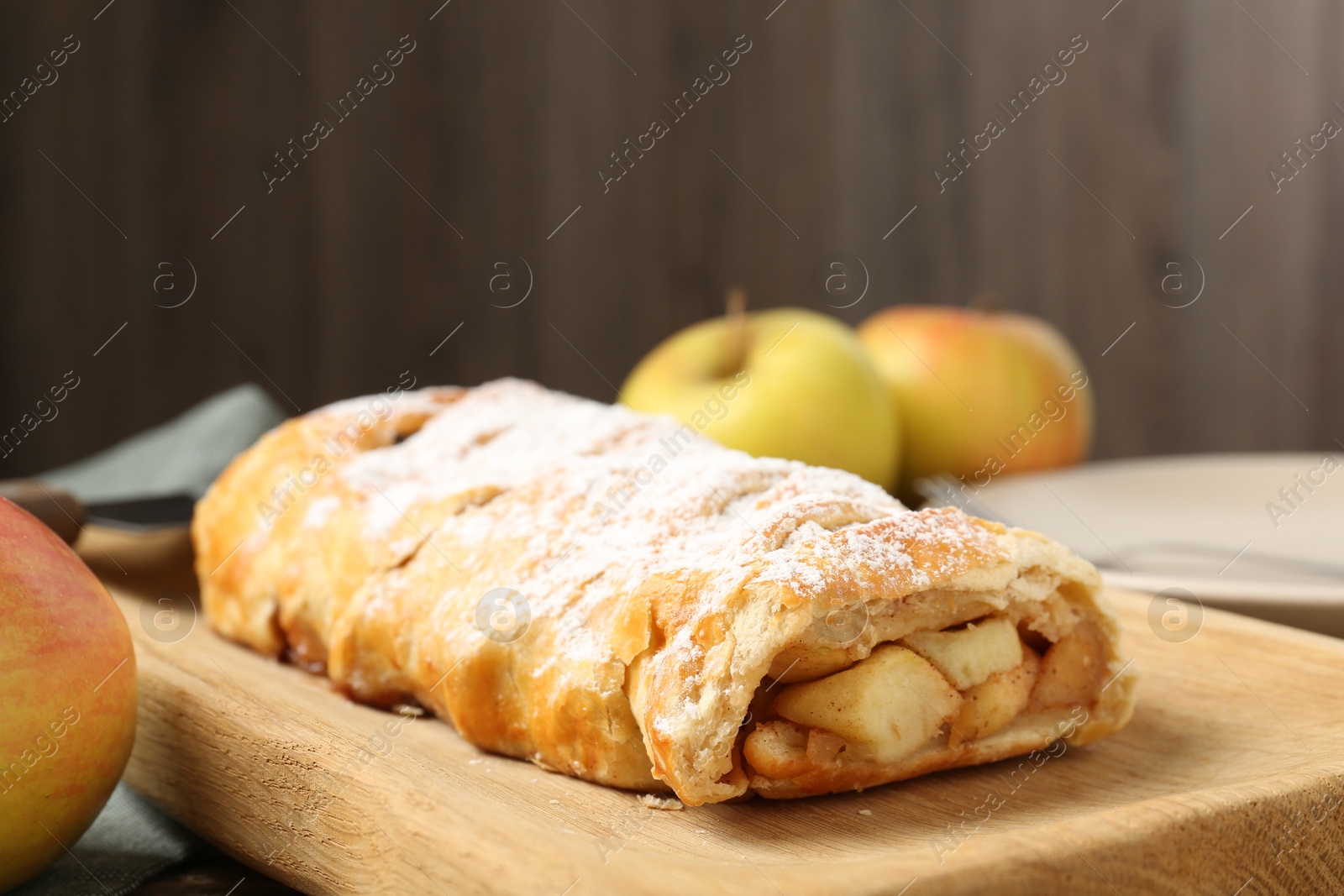 Photo of Delicious strudel with apples and powdered sugar on table, closeup