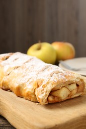 Delicious strudel with apples and powdered sugar on table, closeup