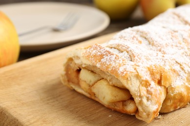 Delicious strudel with apples and powdered sugar on table, closeup. Space for text