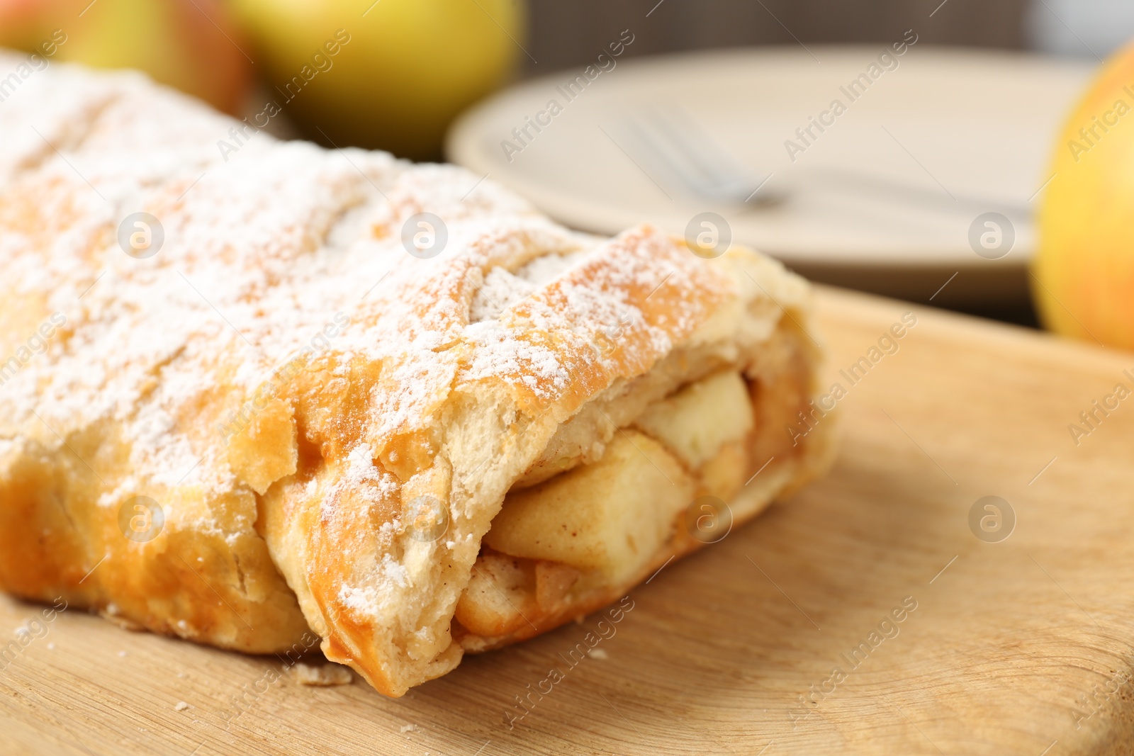 Photo of Delicious strudel with apples and powdered sugar on table, closeup. Space for text