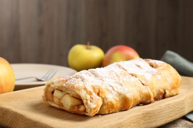 Delicious strudel with apples and powdered sugar on table, closeup