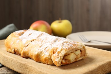 Photo of Delicious strudel with apples and powdered sugar on table, closeup