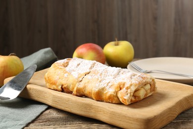 Photo of Delicious strudel with apples and powdered sugar on wooden table, closeup