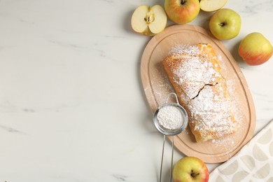 Photo of Delicious strudel with apples and powdered sugar on white marble table, flat lay. Space for text