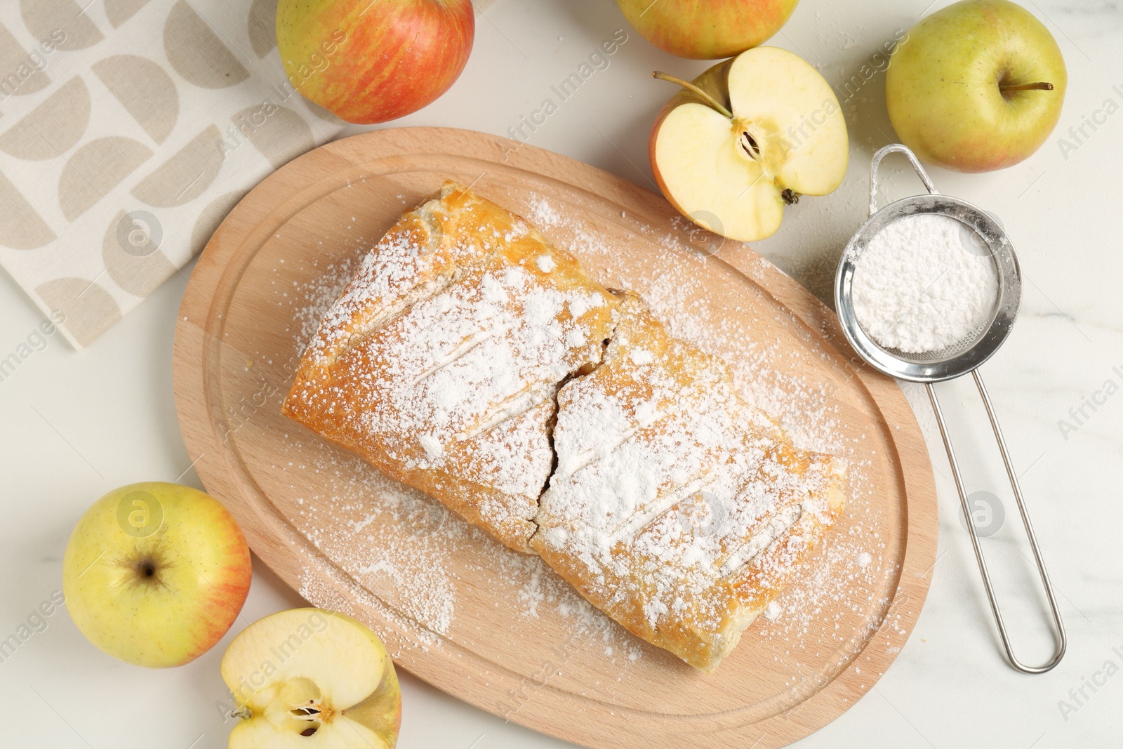 Photo of Delicious strudel with apples and powdered sugar on white marble table, flat lay