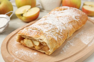 Photo of Delicious strudel with apples and powdered sugar on table, closeup