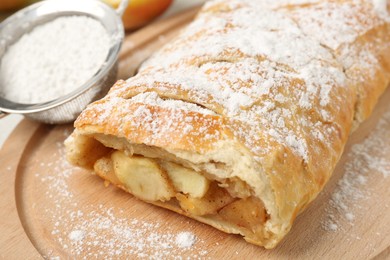 Photo of Delicious strudel with apples and powdered sugar on table, closeup