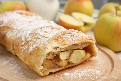 Photo of Delicious strudel with apples and powdered sugar on table, closeup