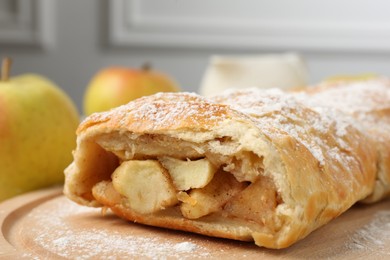 Delicious strudel with apples and powdered sugar on table, closeup