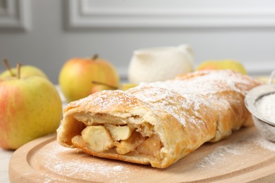 Photo of Delicious strudel with apples and powdered sugar on table, closeup