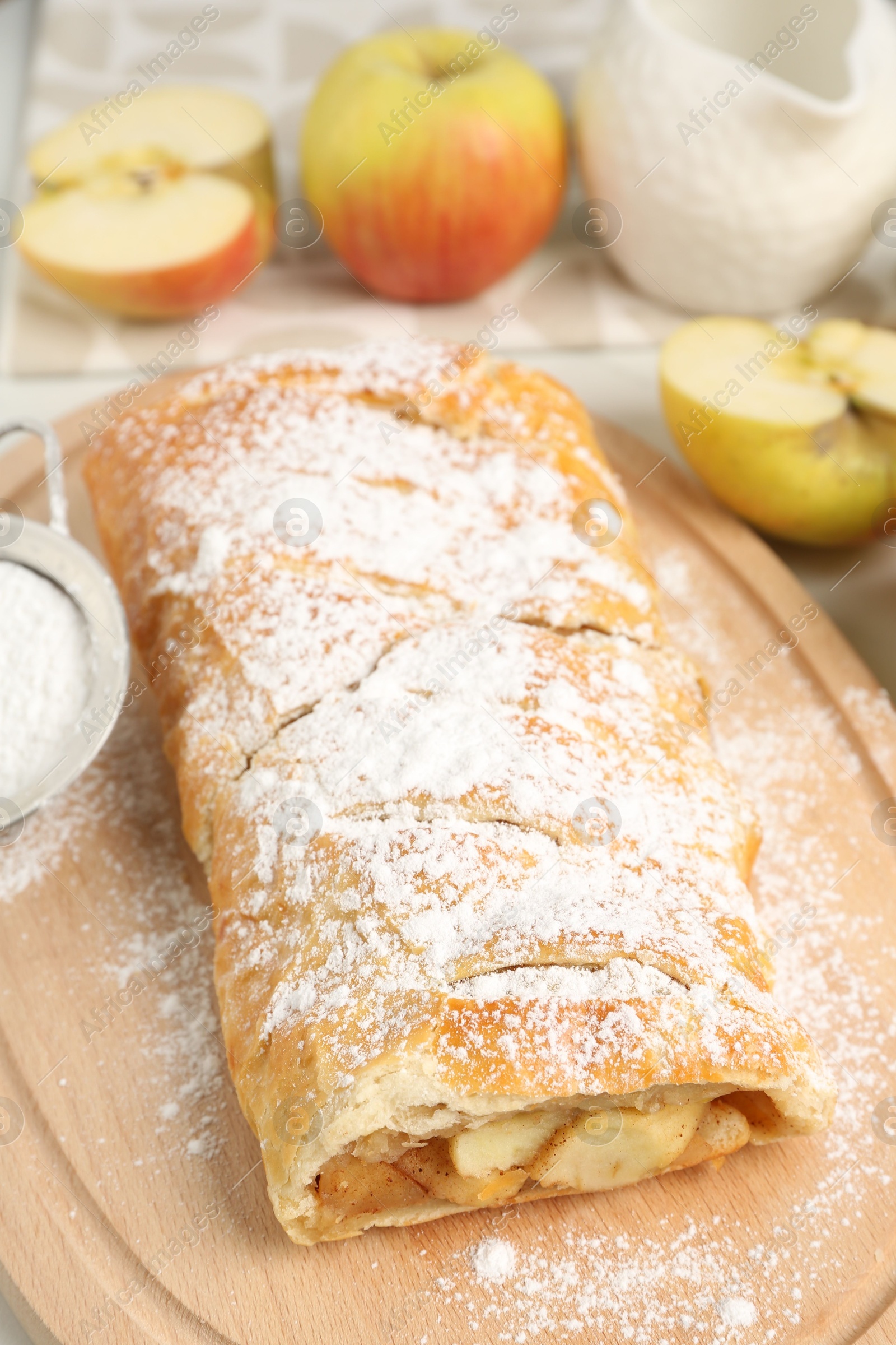 Photo of Delicious strudel with apples and powdered sugar on table, closeup