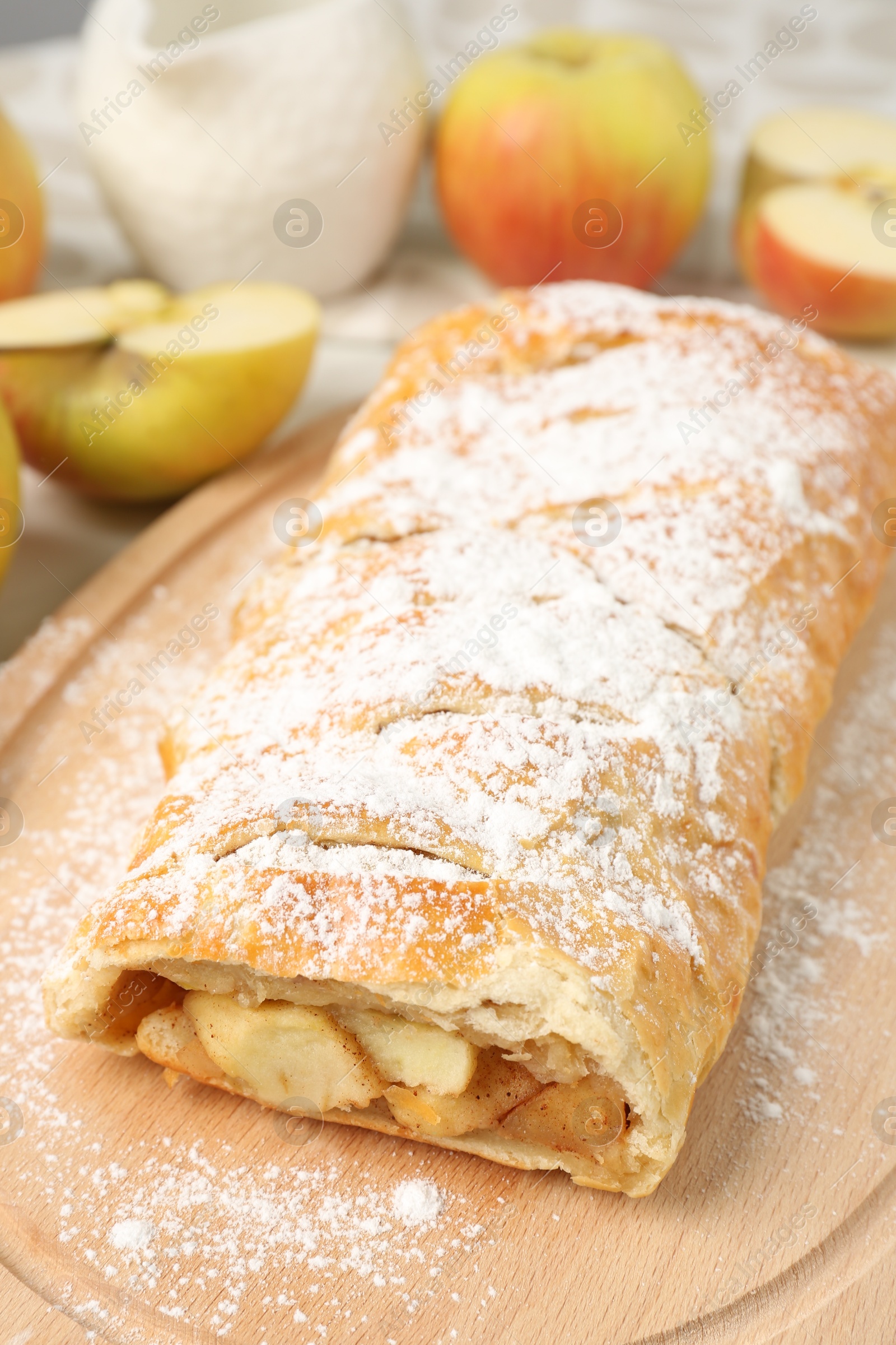 Photo of Delicious strudel with apples and powdered sugar on table, closeup