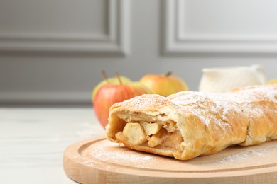 Delicious strudel with apples and powdered sugar on white table, closeup