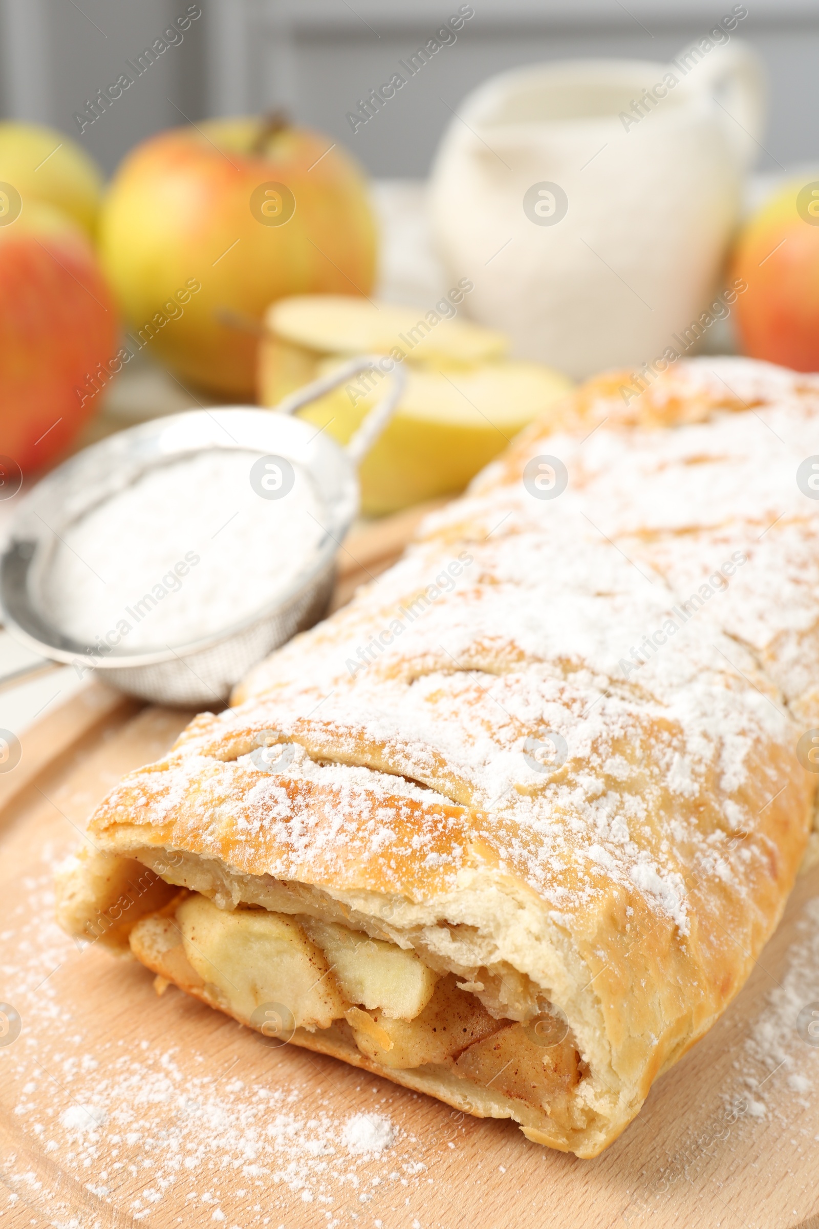 Photo of Delicious strudel with apples and powdered sugar on table, closeup