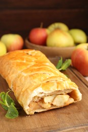 Photo of Delicious strudel with apples and mint on table, closeup