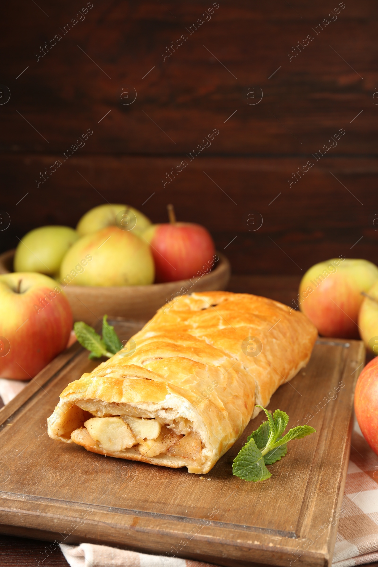 Photo of Delicious strudel with apples and mint on table, closeup