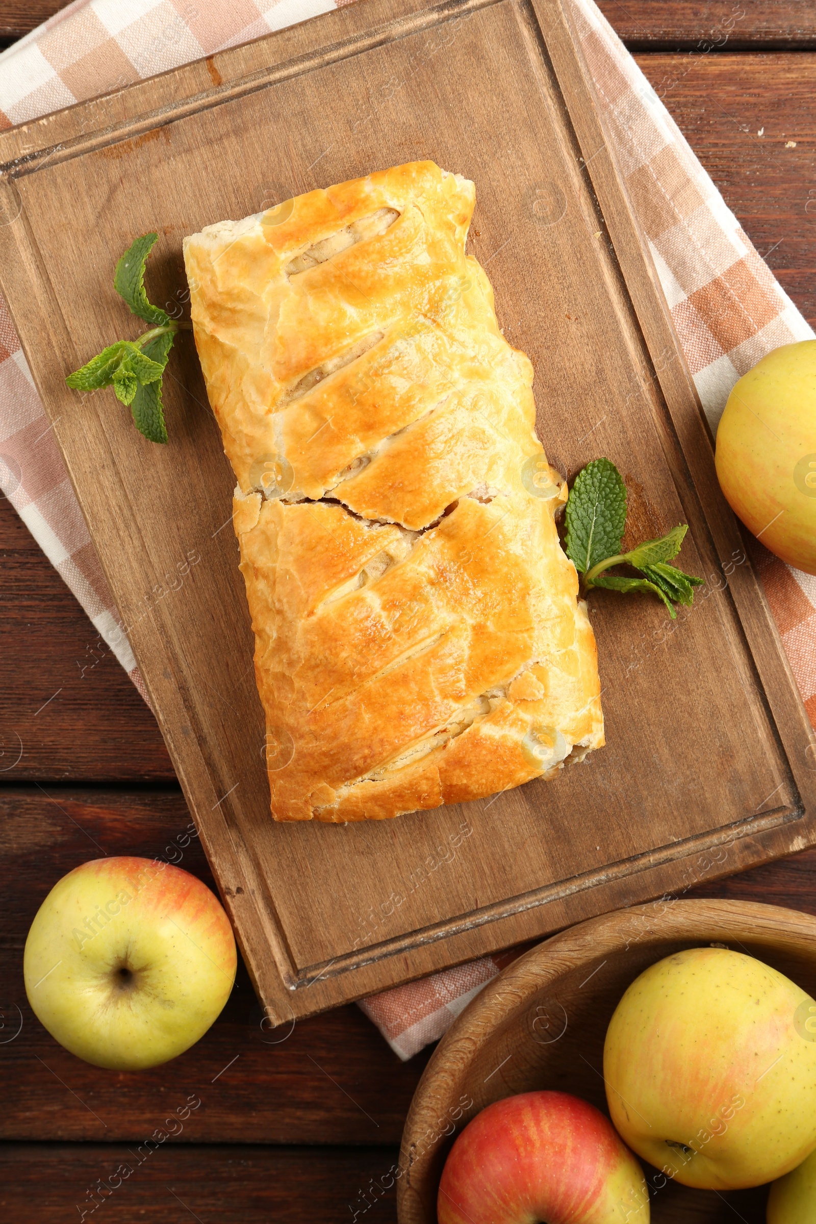 Photo of Delicious strudel with apples and mint on wooden table, flat lay