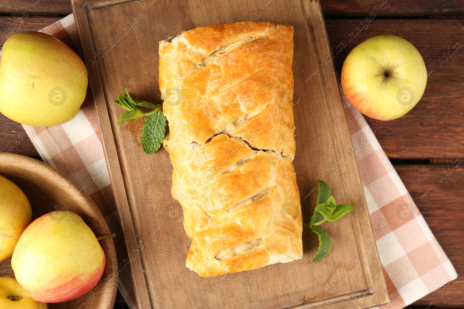 Photo of Delicious strudel with apples and mint on wooden table, flat lay