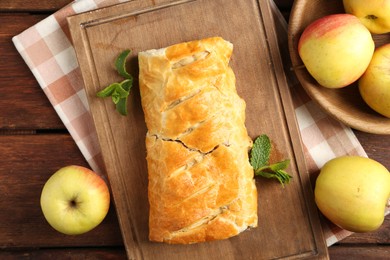 Delicious strudel with apples and mint on wooden table, flat lay